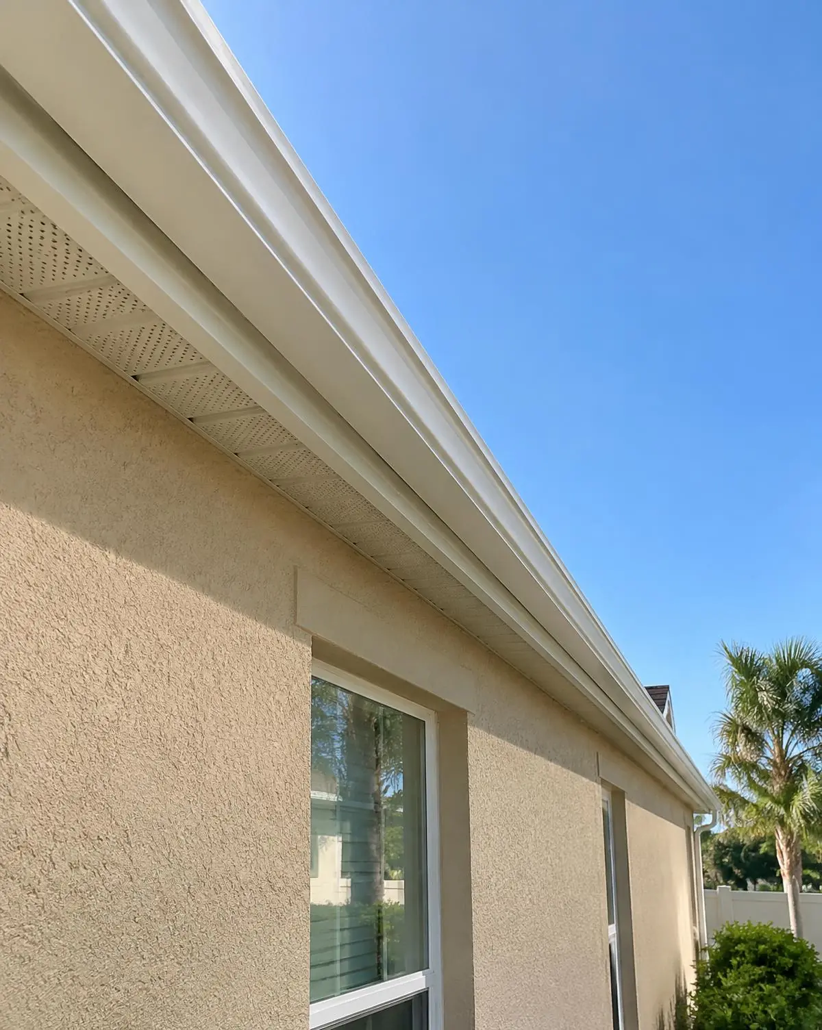 Long continuous white seamless gutter run along a stucco home's eave